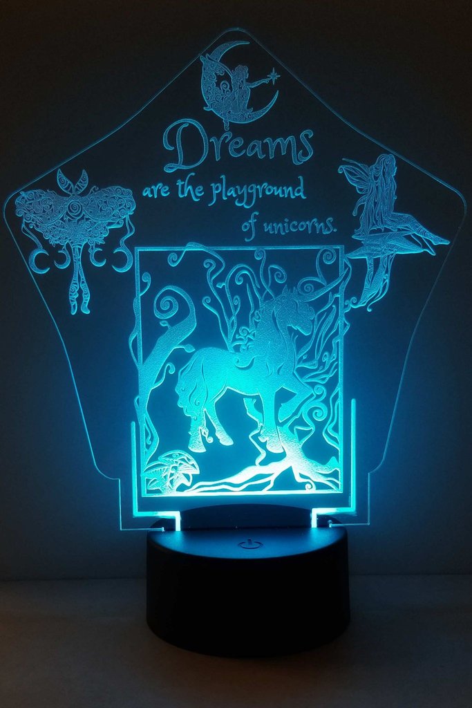 Rounded star shaped transparent night light illuminated with soft light blue light with unicorn centered in forest surrounded by decorative luna moth, fairy with star wand sitting crescent moon, and fairy sitting on mushroom. Text above the unicorn says, "Dreams are the playground of unicorns."